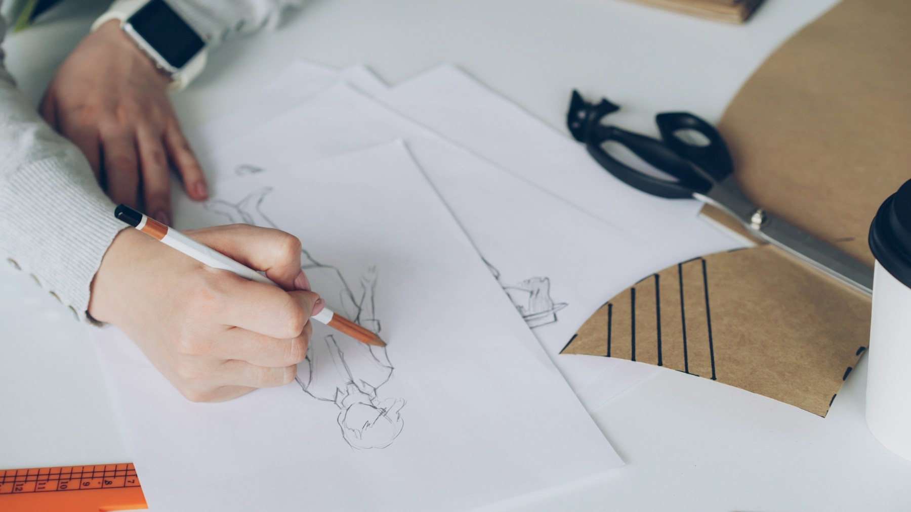 Mãos desenhando uma criação de moda sobre papel
